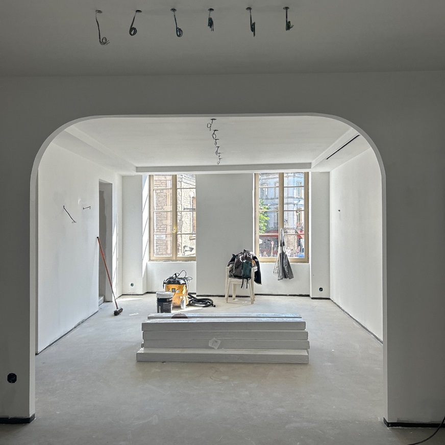 Chantier : grande pièce aux murs enduits vue sous une arche