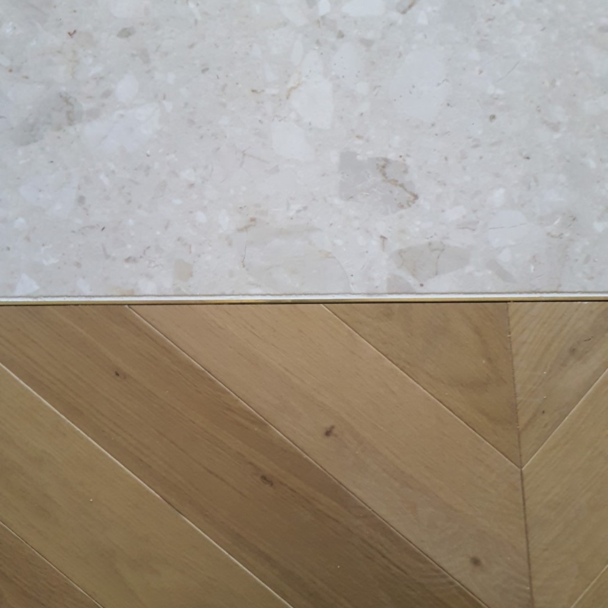 Détail de la jonction entre un sol en terrazzo et un parquet en point de Hongrie